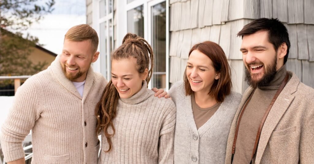 Four friends laughing and bonding outdoors in a cozy winter setting.