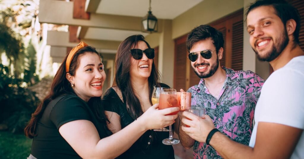 Top Men’s Casual Fashion Essentials for a Smart Everyday Wardrobe Group of friends smiling and toasting drinks outside. Perfect for lifestyle and celebration themes.